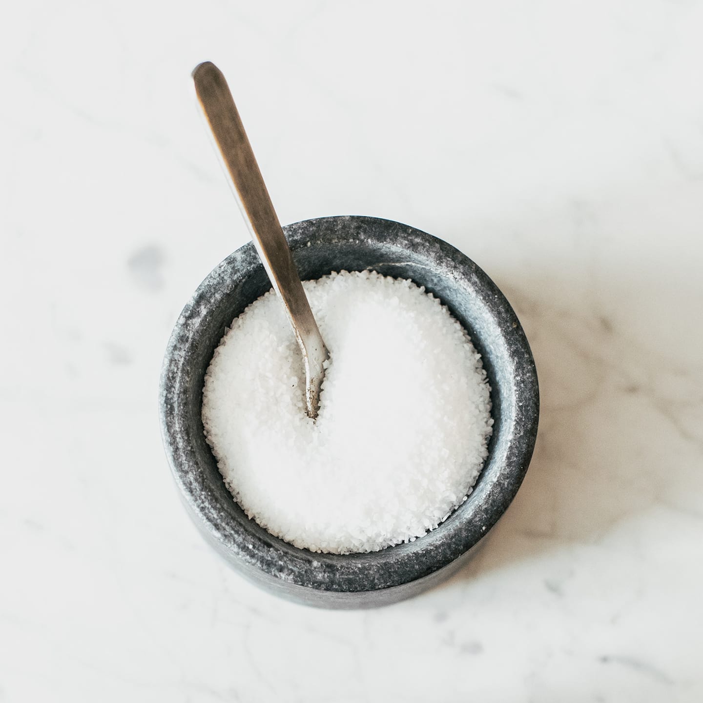 Cup containing white sugar and a spoon