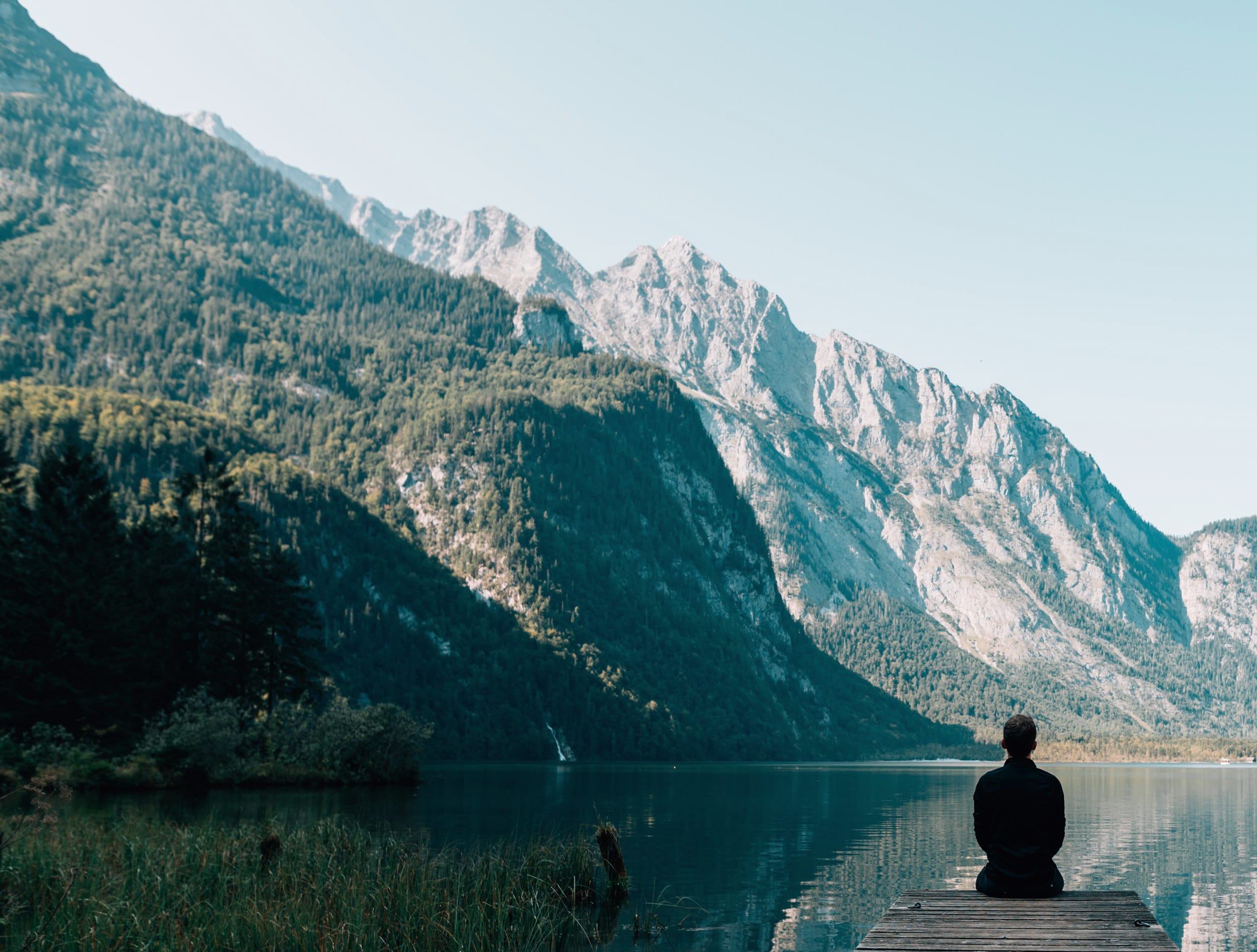 Person sitting quietly and overlooking a beautiful mountain lake
